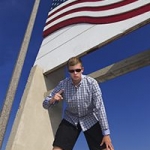 young man under American flag monument.
